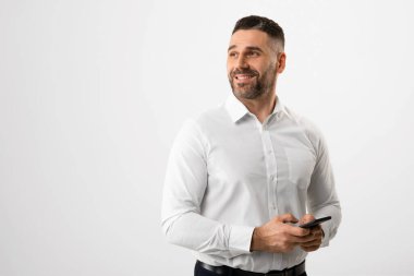 Cep telefonu tutan ve boş alana bakan mutlu işadamı, gri stüdyo geçmişinin başında duran, erkek girişimci mesajlaşması ve reklam cep telefonu teklifi
