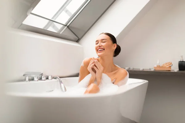 泡泡風呂でリラックスしたお風呂に入り 現代の浴室の屋内で体を洗う幸せな女性 目を閉じてリラックスした女性の入浴 ビューティーデーコンセプト — ストック写真