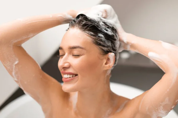 新しいシャンプー 目を閉じた幸せな女性彼女の長い髪のために頭を洗うケア 現代のバスルームで入浴ヘアケアルーチンをお楽しみください ヘアケアの儀式と化粧品の概念 — ストック写真
