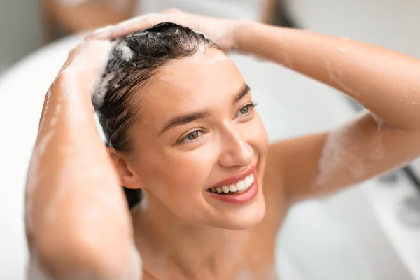 現代の浴室の内湯に座っている髪の世話をする笑顔の女性洗髪頭室 女性の上記のビューは別にシャンプーを適用します ヘアケア化粧品のコンセプト 選択的フォーカス — ストック写真