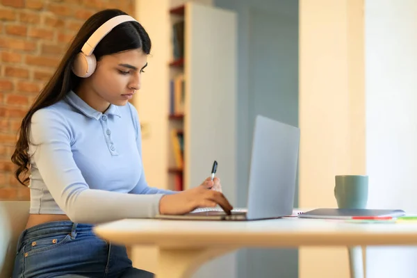 家でノートパソコンで勉強しながら宿題をしながらオーディオコースや音楽を聴きながら真剣な女子高生 — ストック写真