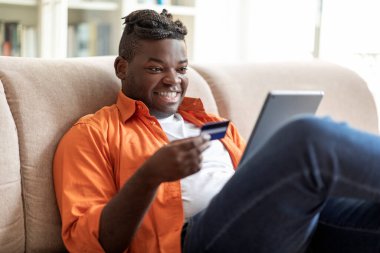 Neşeli, pozitif, saçları örgülü, modern dijital ped ve banka kartı kullanan, internetten alışveriş yapan, internetten alışveriş yapan,