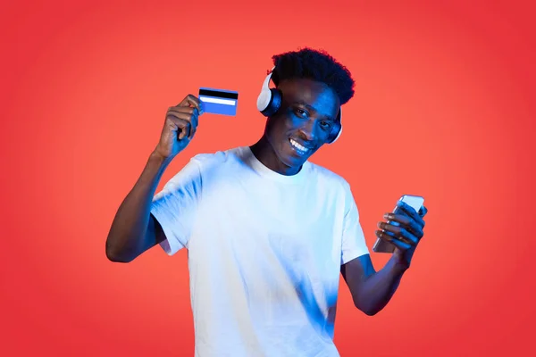 Wesoły Młody Afroamerykanin Korzystający Słuchawek Bezprzewodowych Smartfona Karty Bankowej Kupujący — Zdjęcie stockowe