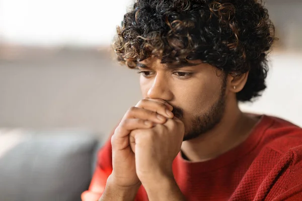 Portrait Of Pensive Young Indian Man Sitting On Couch At Home, Closeup Shot Of Depressed Worried Hindu Guy Thinking About Problems And Looking Away, Suffering Mental Breakdown Or Seasonal Depression