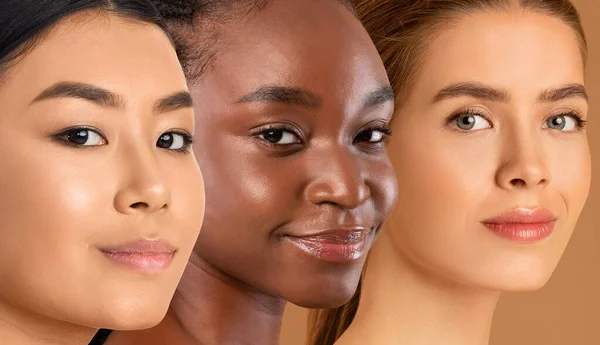 Smiling faces of multiracial ladies posing on beige studio background, three multethnic young women with nude makeup showing nice healthy skin, smiling at camera, collage for skin care concept
