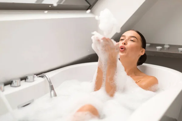 お風呂に入り 泡を吹いて楽しい女性は 現代のバスルームの屋内でリラックス泡を持っています 女性は体のために入浴とケアを楽しんでいます 美の日のコンセプト 選択的フォーカス — ストック写真