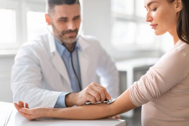 Erkek doktor elle kan basıncını ölçmek için stetoskoplu sphygmomanometre kullanıyor. Hipertansiyon, hipotansiyon, kardiyovasküler hastalıklar kontrol konsepti
