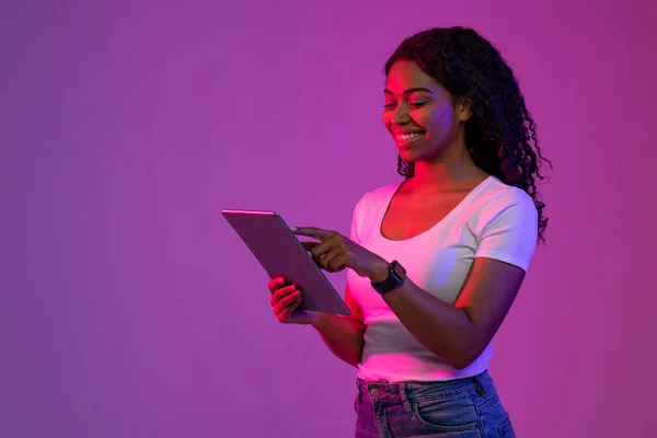 Gülümseyen Siyah Kadın Dijital Tablet Kullanırken Mor Arkaplan Üzerinde Neon — Stok fotoğraf