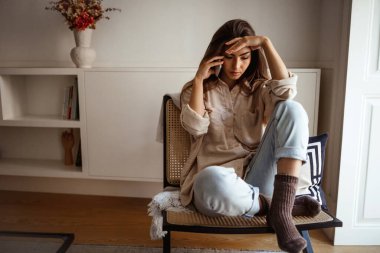 Mutsuz üzgün milenyum melez bayanı telefonla arıyor, konuşuyor, kötü haberlerden muzdarip sandalyeye oturuyor, odanın içinde baskı var. Sorunlar, stres, evde uzaktan iletişim