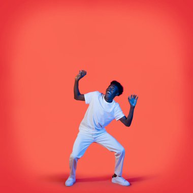 Neşeli, heyecanlı, beyaz giysili Afro-Amerikan bir adam ağır bir şey taşıyor, siyah bir adam elini kaldırıyor, başının üstündeki fotokopi odasına bakıyor, kırmızı arka plan, neon ışığı.