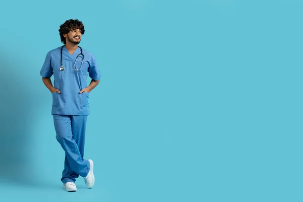 파란색 작업복을 멋지고 잘생긴 복제품을 주머니에 의사와 웃으며 스튜디오 배경에 — 스톡 사진
