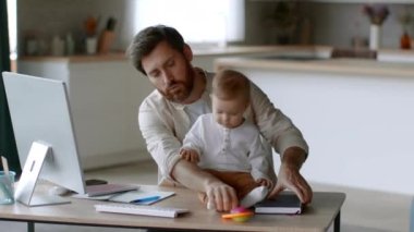 Babalık izni ve uzaktan çalışma. Genç adam bilgisayarda çalışıyor ve aktif küçük kızını tutuyor. Ofiste zaman sıkıntısı çekiyor, çekim takibi yapıyor, yavaş çekim yapıyor.