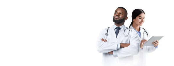 两名医生身穿制服站在白色背景下 男医生和女医生站在灯光背景下 女医生拿着数码记事本 大学生 复制空间 — 图库照片