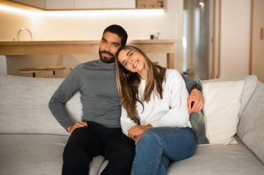 Mutlu uluslararası milenyum çiftleri kucaklaşır, kanepede oturur, birlikte vakit geçirir, minimalist oturma odasında televizyon izleriz. Evde dinlen, aşk ve ilişkiler, reklam ve teklif