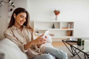 Bin yıllık melez bir ırk kadınının kablosuz kulaklıklarla telefona bakması, mesaj okuması, sohbet etmesi, boş zamanların tadını çıkarması oda içi video araması yapması ne güzel. Uzaktan iletişim uygulaması, evde müzik dinlemek