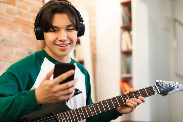 Asiatico Giovanotto Ragazzo Imparare Giocare Elettrico Chitarra Utilizzando Smartphone Applicazione — Foto Stock