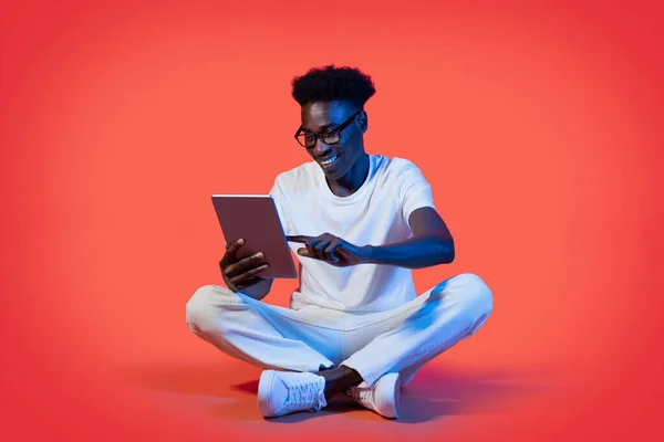 Szczęśliwy Młody Afroamerykanin Okularach Siedzący Podłodze Korzystający Nowoczesnego Komputera Cyfrowego — Zdjęcie stockowe