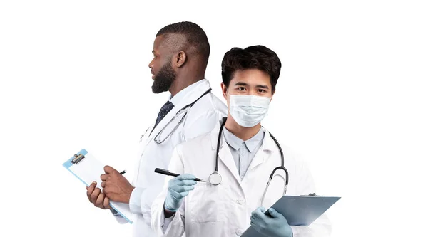 医疗服务 两名男性医生站在白种人的背景上 双手拿着剪贴板准备提供治疗的多种族保健工作者的综合形象 — 图库照片