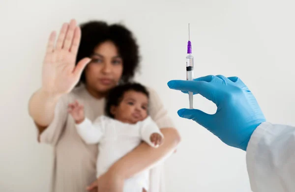 深刻な愛情の若いアフリカ系アメリカ人の女性が腕の中で赤ちゃんを保持し 注射器で医師から手で停止ジェスチャーを作る ぼやけた 母は予防接種 ベビーケア 抗毒素から子供を保護します — ストック写真