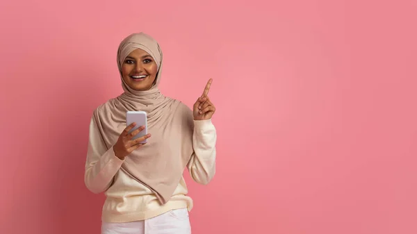 Oferta Especial Sonriente Dama Musulmana Hijab Sosteniendo Teléfono Inteligente Señalando —  Fotos de Stock