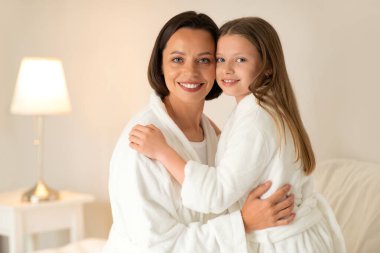 Gülümseyen Avrupalı bin yıllık bayan ve bornozlu küçük kız yatakta sarılır, birlikte dinlenir, beyaz yatak odasının içinde boş zaman ve hafta sonu geçirirler. Günaydın güzellik, ilişki ve aşk.