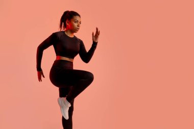 Atletik Afrikalı Amerikalı kadın koşmadan önce ısınıyor, şeftali neon stüdyosu geçmişi, fotokopi alanı eğitimi alıyor. Spor salonundaki kadın dirsek dirseğe çatırdıyor. Spor motivasyonu kavramı