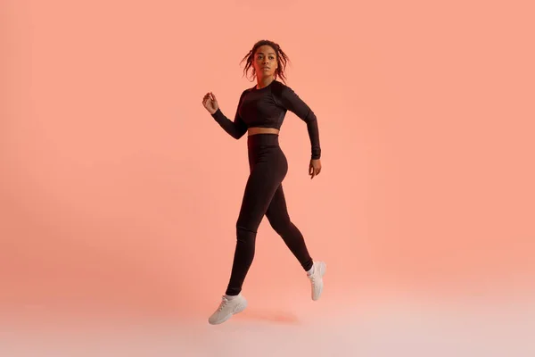 黒人女性アスリートはジャンプ ランニング ネオンスタジオの背景でのトレーニング中の運動 フィットネスワークアウトとスポーツモチベーションコンセプト — ストック写真