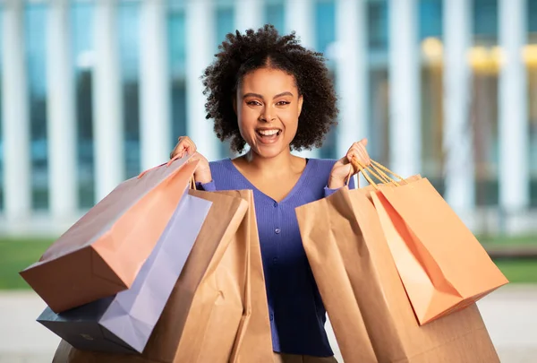 快乐的黑人妇女拿着纸袋微笑着站在城市地区的户外拍照 女购物者享受周末的销售旺季 消费主义概念 — 图库照片