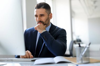 Bilgisayarla çalışan konsantre orta yaşlı erkek girişimci, ekrana bakıyor ve düşünüyor, ofis içinde çalışan odaklanmış iş adamı, serbest alan