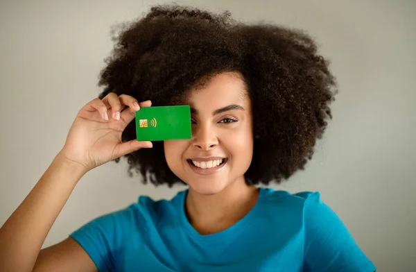 陽気な面白いかなり若い巻きアフリカ系アメリカ人の女性が目にクレジットカードを入れて グレーの背景 スタジオ クローズアップでオンラインショッピングをお楽しみください 家での金融 キャッシュバック — ストック写真