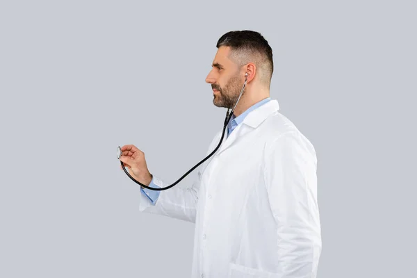 Zdjęcie Profilowe Lekarza Białym Płaszczu Słuchającego Stetoskopem Odizolowanym Szarym Tle — Zdjęcie stockowe