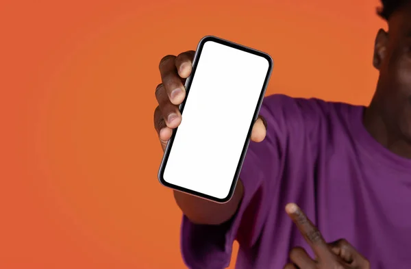 オンラインオファー モバイルアプリ アフリカ系アメリカ人の男の作物は 現代の携帯電話を保持し 赤のスタジオの背景に白い空白の画面を指して 広告のためのモックアップ コピースペース — ストック写真