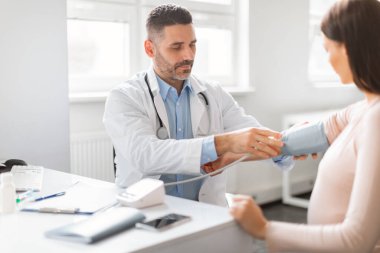 Jinekolog erkek doktor. Hasta hamile bayanın arteriyel kan basıncını ölçüyor. Muayene sırasında hasta bir kadın kendini iyi hissetmiyor.