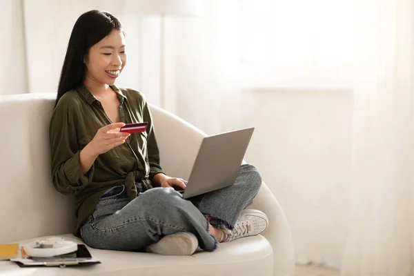 明るい魅力的な若いアジアの女性の笑顔ソファの上に足を座って 自宅で現代のPcのラップトップと銀行カードを使用して インターネット上の商品やサービスの支払い スペースのコピー — ストック写真