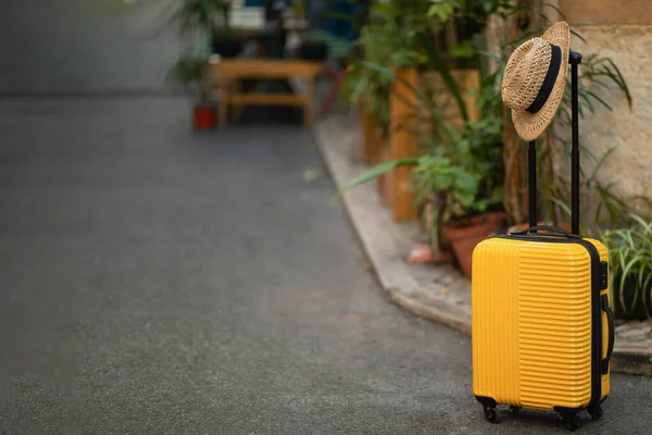 植物と道路上の帽子と黄色の大きなスーツケース 観光客のための旅行のためのアクセサリーフリースペース 閉じると 旅行休暇 夏休み アクティブなライフスタイルのコンセプト — ストック写真