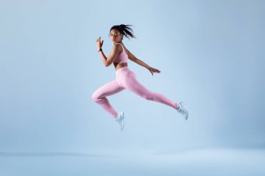 Eğitim konsepti. Spor giyinen, atlayan ya da koşan, neon mavisi stüdyo arka planı üzerinde egzersiz yapan, serbest alan, tam boy. Enerji ve spor