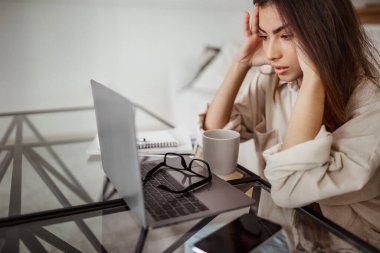 Mutsuz milenyum melezi bir kadın laptopa bakıyor, oda içinde aşırı çalışma, baskı ve baş ağrısı çekiyor. İşle ilgili sorun, uzaktan iş, evde son teslim tarihi