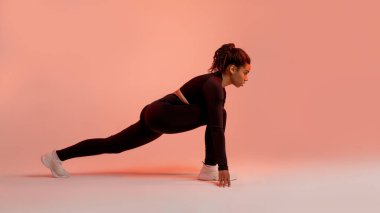 Spor kıyafetli Afro-Amerikan bayan antrenmandan önce bacaklarını esnetiyor, spor eğitimi için hazırlanıyor neon arka plan, stüdyo çekimi, yan görüş, panorama
