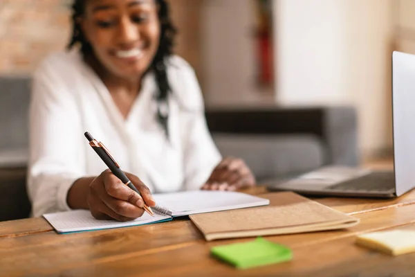 ノートパッドで書く幸せな黒人女性職場でノートを取り ノートパソコンを使用して インターネットからの情報を注目し 女性の手に焦点を当て クローズアップ — ストック写真