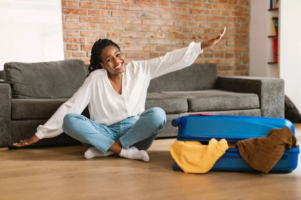 Χαρούμενη Μαύρη Γυναίκα Κάθεται Στο Πάτωμα Κοντά Συσκευασμένο Βαλίτσα Και — Φωτογραφία Αρχείου