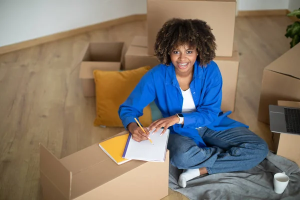 Einkaufsplanung Glückliche Schwarze Frau Die Nach Ihrem Umzug Checkliste Erstellt — Stockfoto