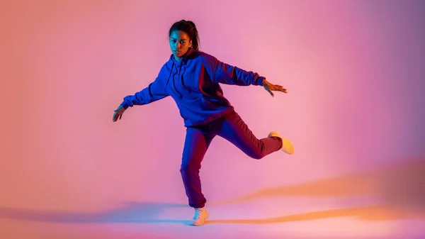 stock image Dancing style. Black lady making hip-hop tricks on gradient pink neon background, panorama, full length. Youth culture, style and fashion. Concept of dance, hobby, dynamics, movement, action, ad