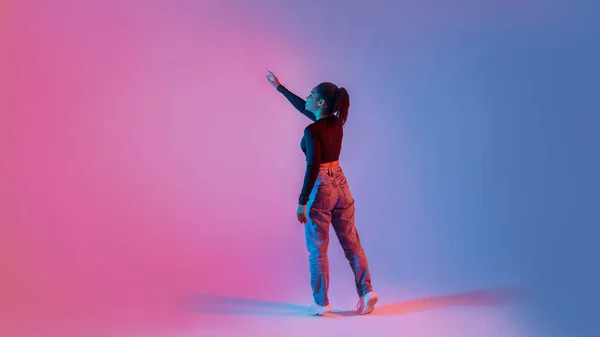 仮想インターフェイスを使用して若い黒人女性のバックビュー 想像力豊かな画面に触れる ネオンカラフルな背景に立って 無料のスペースでバナーデザイン パノラマ — ストック写真