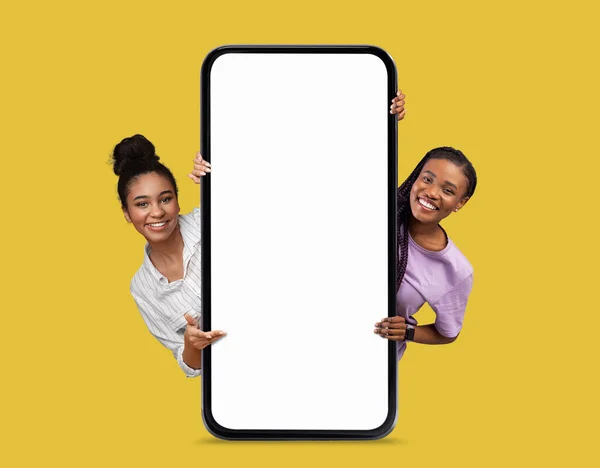 Oferta Online Duas Mulheres Negras Sorridentes Bonitas Espreitando Atrás Smartphone — Fotografia de Stock