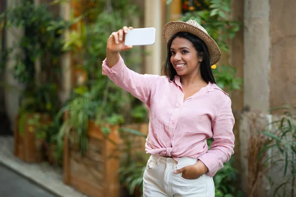 幸せな若い黒の女性は カジュアルな携帯電話で自撮りを取り 新しい都市での旅行をお楽しみください ソーシャルネットワークのためのビデオを撮影 休暇と夏の旅行 ブログのためのアプリ ビデオ通話 — ストック写真