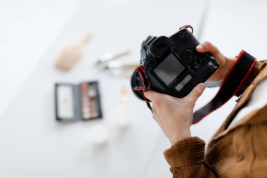 Fotostudio 'da çalışan profesyonel erkek içerikli fotoğrafçı, kozmetik çekimleri, boş ekran ile modern fotoğraf makinesine odaklan.