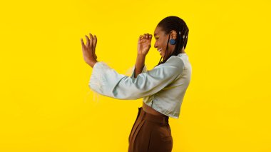 Dur bir bakayım. Heyecanlı Afro-Amerikan Kadın Spyglass 'ın elinden görünmeyen teleskopu tutuyormuş gibi yapıyor ve sarı arka plan üzerinden stüdyoda poz veriyor. Panorama, Yan Görünüm