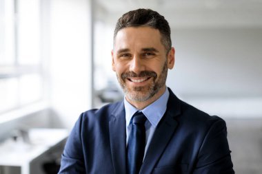 Portrait of happy confident middle aged businessman in suit looking and smiling at camera, posing in office interior, free space. Ceo manager and boss, successful work, career concept clipart