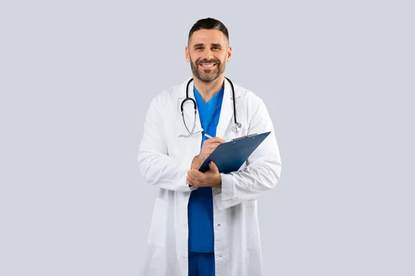 Πορτρέτο Του Χαμογελαστού Αρσενικού Γιατρού Στολή Κρατώντας Πρόχειρο Κοιτάζοντας Την — Φωτογραφία Αρχείου
