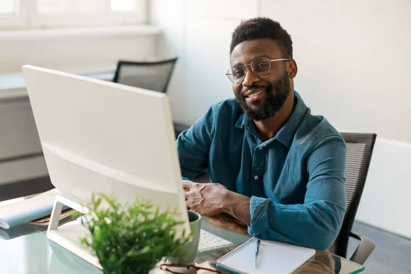 Pozitivní Černý Obchodník Brýlích Usmívá Kamery Sedí Před Počítačem Pracovní — Stock fotografie